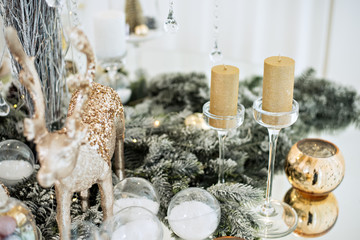 New Year's festive glass table setting. Greeting card. There are wine glasses and cutlery in the branches of the Christmas tree. Decorated with gold candles, deer, stars, balls. Copy space, bokeh fir