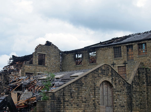 a large ruined industrial destroyed by a fire with collapsing walls and roof and burned timbers
