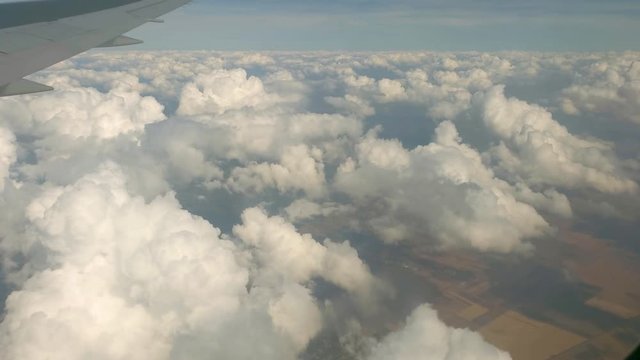 Aerial view of clouds and the Earth from airplane window. View from airplane window flying over clouds.
