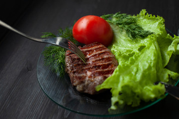 Beef steak with salad and tomato on the plate with fork