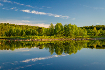 Fototapeta na wymiar stones, crystal water and green trees on the lake Kovdozero in Zelenoborsky village near Kandalaksha. Kola Peninsula, Russia.