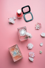 lady set with cosmetics and flowers around pink background. flat lay
