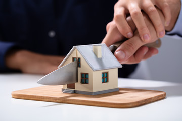 Close-up Of Couple Cutting The House Model With Knife