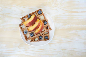 Chocolate Belgian waffles with fruits and berries on white wooden background. Delicious breakfast. Top view