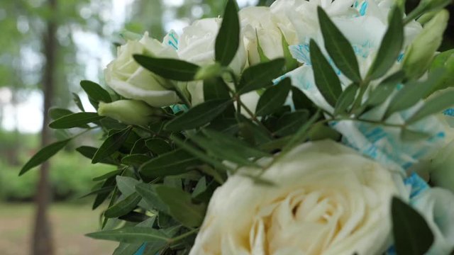A bouquet of flowers tied with a cyan ribbon lies on a hemp. Shooting with a 3-axis motorized gimbal stabilizer.