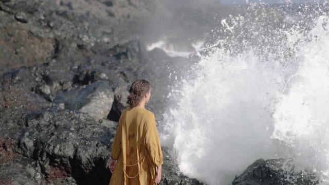 A girl's standing next to a Blowhole waiting for the water explosion