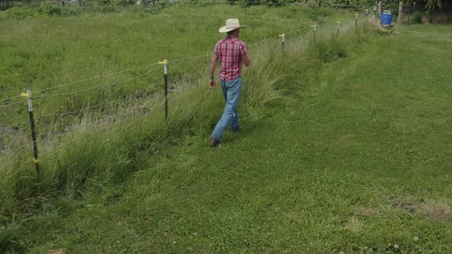Cowboy rancher walking along a fence