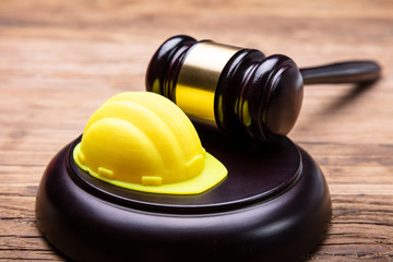 Yellow Hard Hat And Gavel Arranged On Wooden Desk