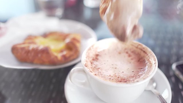 Vintage POV shot of having breakfast with a cup of milk and coffee cappuccino and a brioche in a cafeteria or at home. Personal perspective of dunking a croissant into an Italian cappuccino. 