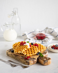 Belgian waffles with fresh berries jn the white background.