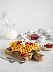 Belgian waffles with fresh berries jn the white background.
