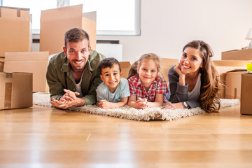 Family of four on the floor of their new apartment smiling