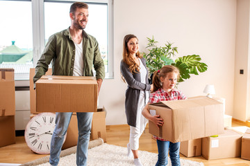 Happy couple and their daughter moving in a new apartment