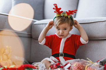 Funny baby boy weared in Santa hat with New Year's decorations.