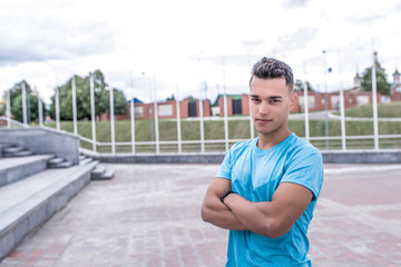 Athlete man smiles, looks carefully, close-up, serious look of trainer, summer in city, sports shirt, motivation youth lifestyle, outdoor training. Motivation active lifestyle. Free space for text.