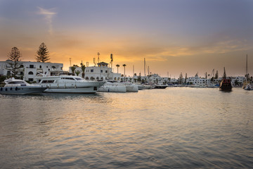 Amazing marina in Port El Kantaoui, Tunisia, colorful blue and golden sky, reflections in the sea and beautiful yachts and white villas and hotels