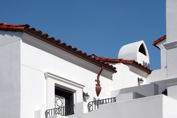 Low angle sectional outside view of a part of a downtown building in the typical Spanish heritage red roof style of Santa Barbara on a bright summer day