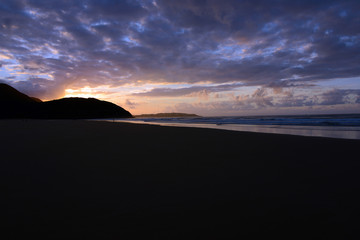 empty beach in Portugals Algarve with reflecting clouds in wet sand during sunset