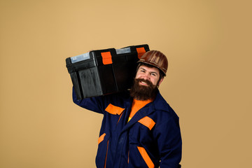 Tools for repair. Repair kit. Builder man in suit carrying tool box. Repairman in overall hold toolbox. Man with tool box. Builder in protective helmet with toolbox. Repair. Handyman concept.