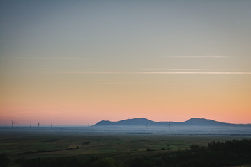 Naklejka na ściany i meble View on a distant mountains in a plain on a foggy morning