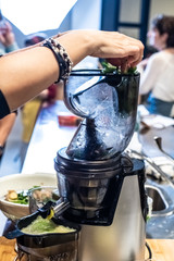 Woman preparing a healthy green juice in a blender.
