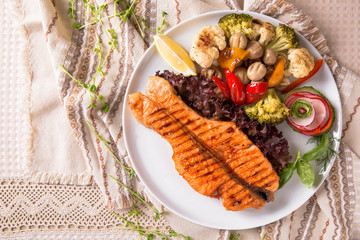 Grilled salmon steak. Juicy delicacy red fish on a plate with a salad of fried vegetables. Balkan cuisine. Restaurant menu