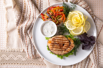 Grilled seabass, mullet, or dorado. Juicy delicacy fish on a plate with a salad of fried vegetables. Balkan cuisine. Restaurant menu