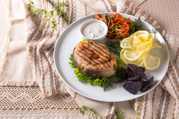 Grilled seabass, mullet, or dorado. Juicy delicacy fish on a plate with a salad of fried vegetables. Balkan cuisine. Restaurant menu