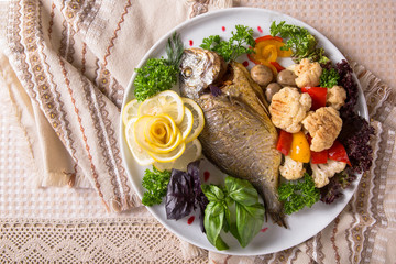 Grilled Dorado fish. Juicy delicacy fish on a plate with a salad of fried vegetables. Balkan cuisine. Restaurant menu