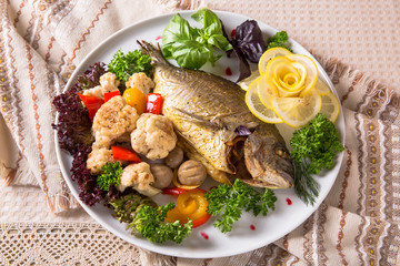 Grilled Dorado fish. Juicy delicacy fish on a plate with a salad of fried vegetables. Balkan cuisine. Restaurant menu