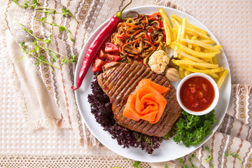 Grilled beef steak. A juicy piece of meat with vegetables, mushrooms, sauce and French fries. Restaurant menu. Isolated on white