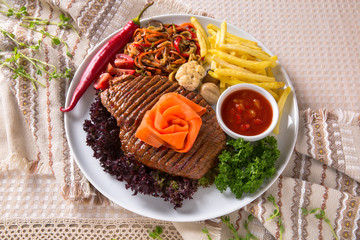 Grilled beef steak. A juicy piece of meat with vegetables, mushrooms, sauce and French fries. Restaurant menu. Isolated on white