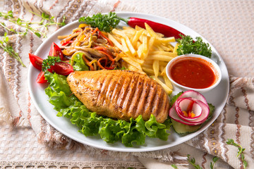 Grilled chicken fillet. A juicy piece of meat with vegetables, mushrooms, sauce and French fries. Restaurant menu. Isolated on white
