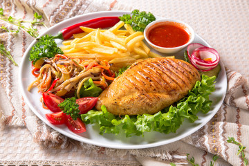 Grilled chicken fillet. A juicy piece of meat with vegetables, mushrooms, sauce and French fries. Restaurant menu. Isolated on white