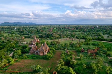 Fototapeta na wymiar aerial view of sunset of Bagan Myanmar. Ancient pagoda in wide green landscape. White clouds skyline 