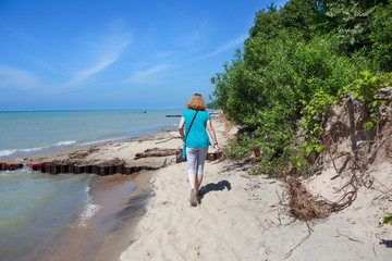 Woman walking at the beach on Lake Michigan, a portion of the beach is gone due to high water and...