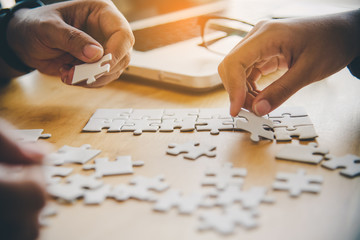 Business team handle a piece of white puzzles that are about to drop to get a complete worksheet -...