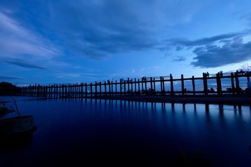 wide angle of U Bein Bridge at sunset blue hour in Mandalay Myanmar. The oldest and longest teak bridge in the world. Long exposure