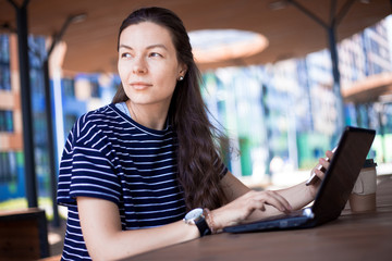 Close-up, portrait of a serious, gently smiling girl student, freelancer, blogger working at a...