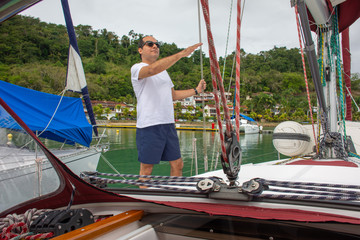 Delighted tourist man on sailboat boat trip during vacation