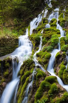 Close up of an alpine waterfall flowing between moss-covered rocks