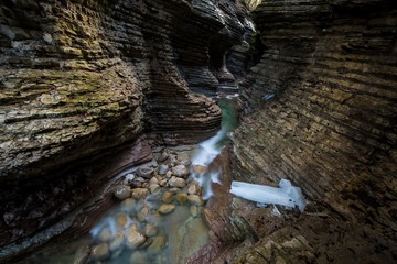 Wide angle shot of the interior of a stratified slot canyon with a small creek running in the middle