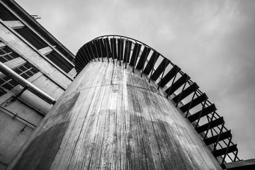 Black and white shot of an old abandoned industrial silo, with spiral staircase running around its side © Roberto