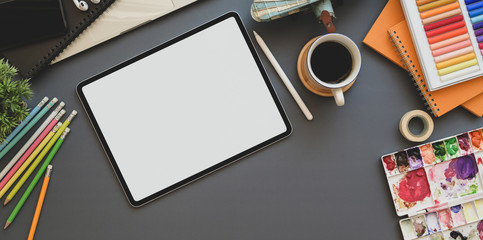 Top view of professional artist workplace with blank screen tablet and painting tools