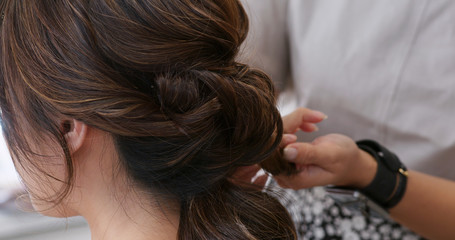 Fototapeta premium Hairdresser creating a hairstyle for bride in salon
