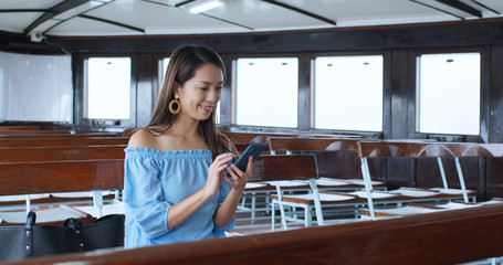 Woman use of smart phone and sit on star ferry in Hong Kong