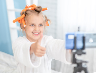 Young girl showing thumbs up, asking online audience to like and subscribe