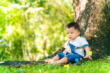 Infant baby boy playing on green meadow city park