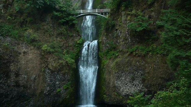 Bottom up tilt of a rocky cliff and free falling water of Multnomah waterfall