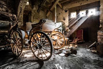 In an old abandoned basement lies an ancient coach, lit by sunrays entering from small windows